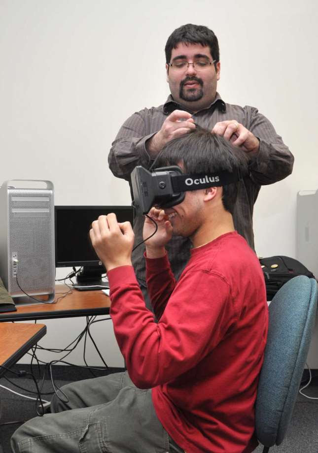 Ibrahim Yucel, a SUNY Polytechnic Institute assistant professor and faculty lead for the school's new interactive media and game design degree program, works with a student using the Oculus Rift virtual-reality headset.