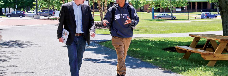 Faculty member John Marsh walks with student in front of Student Center