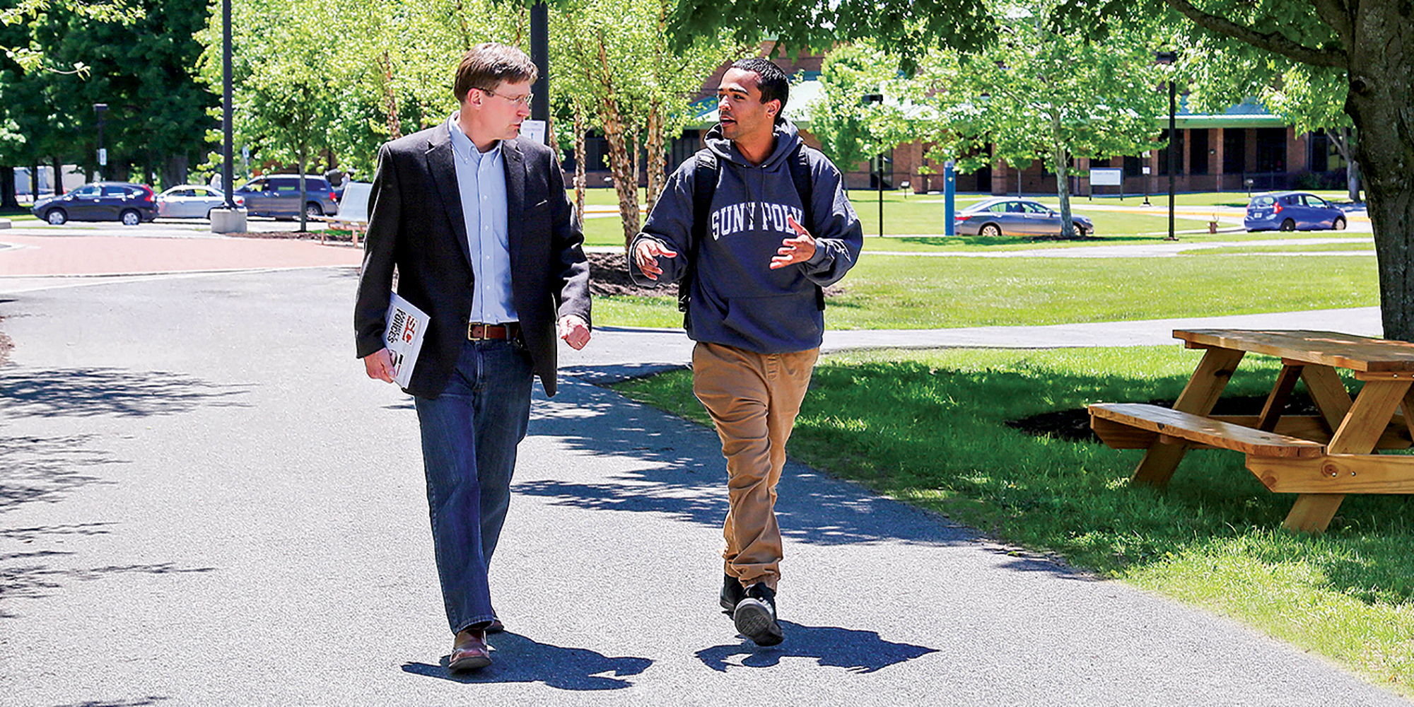 Faculty member John Marsh walks with student in front of Student Center