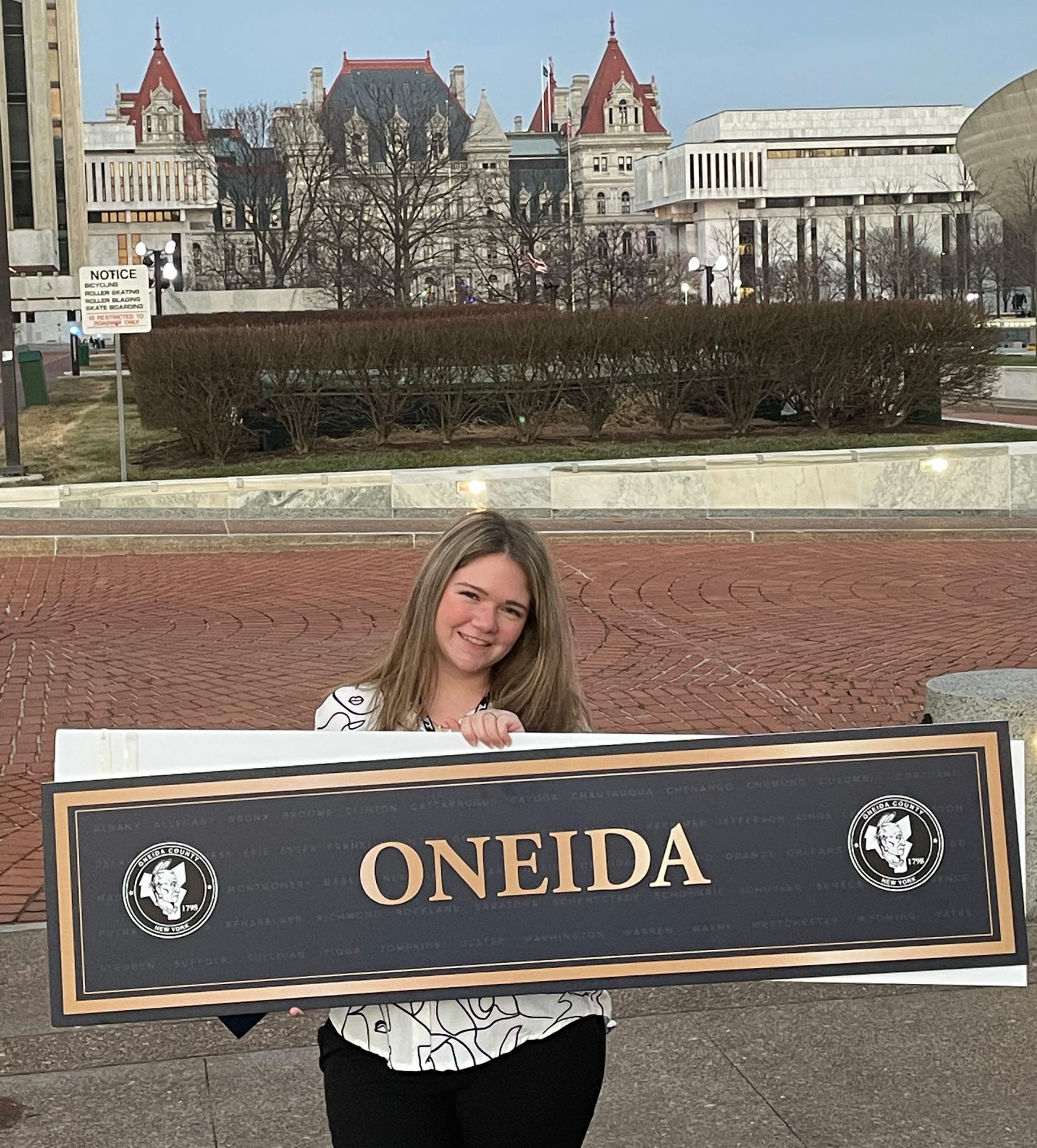 Bailey Wadsworth holding up an Oneida County sign