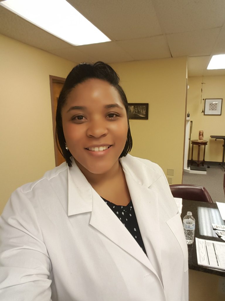 Stacey Flenory in her nursing coat in the office preparing to assist patients