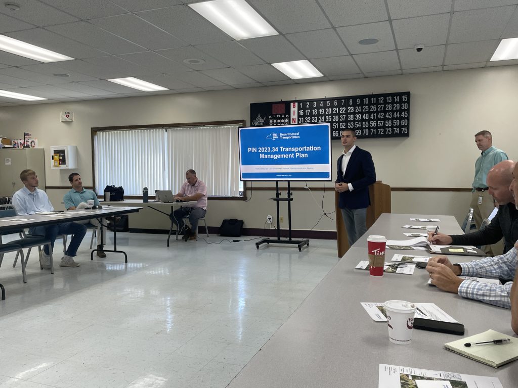 Roach in front of an audience giving a presentation on the New York State DOT Transportation Management Plan.