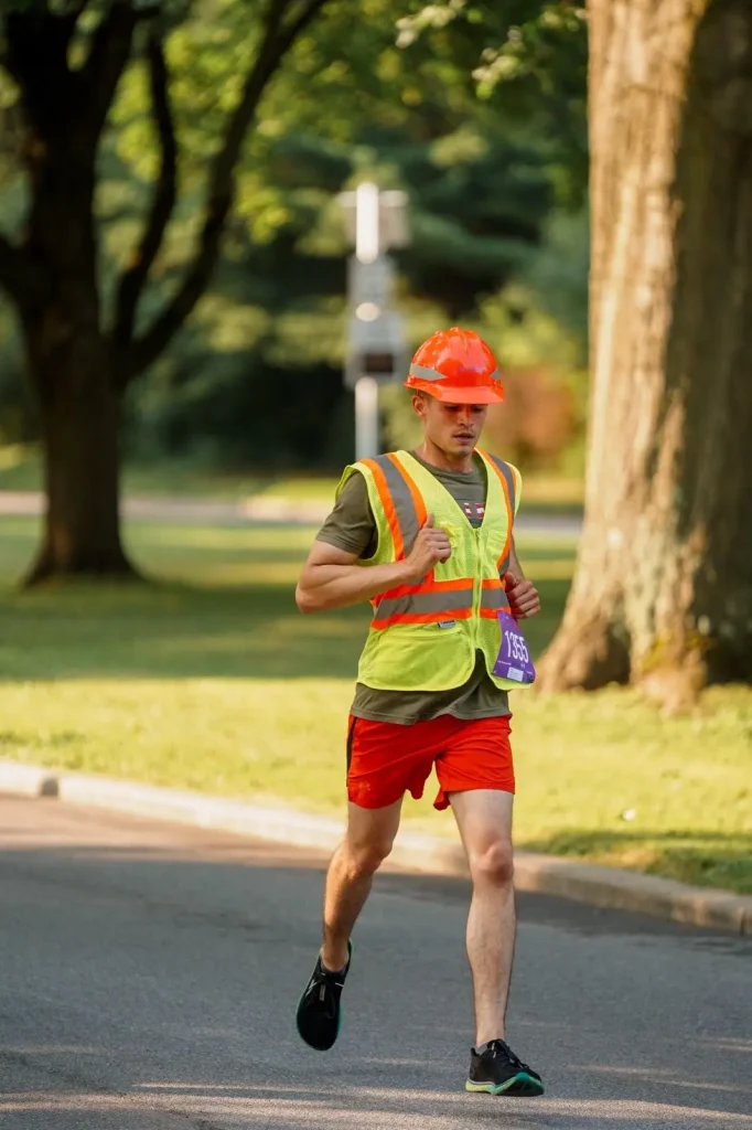 Roach running the boilermaker, which is a 15K road race, with a work helmet and yellow work vest repping the NYSDOT
