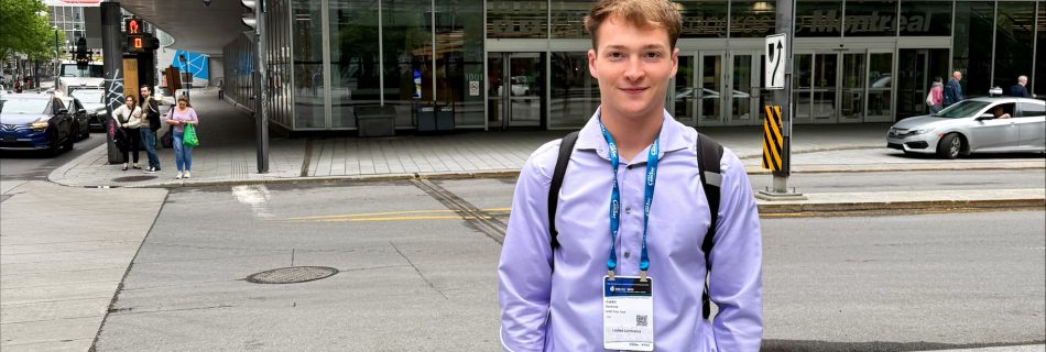 SUNY Poly Senior Justin Osmond pictured in Montreal where he presented at a conference. He is wearing professional attire, light blue dress shirt, dark slacks, brown dress shows. He is has darker blonde hair.