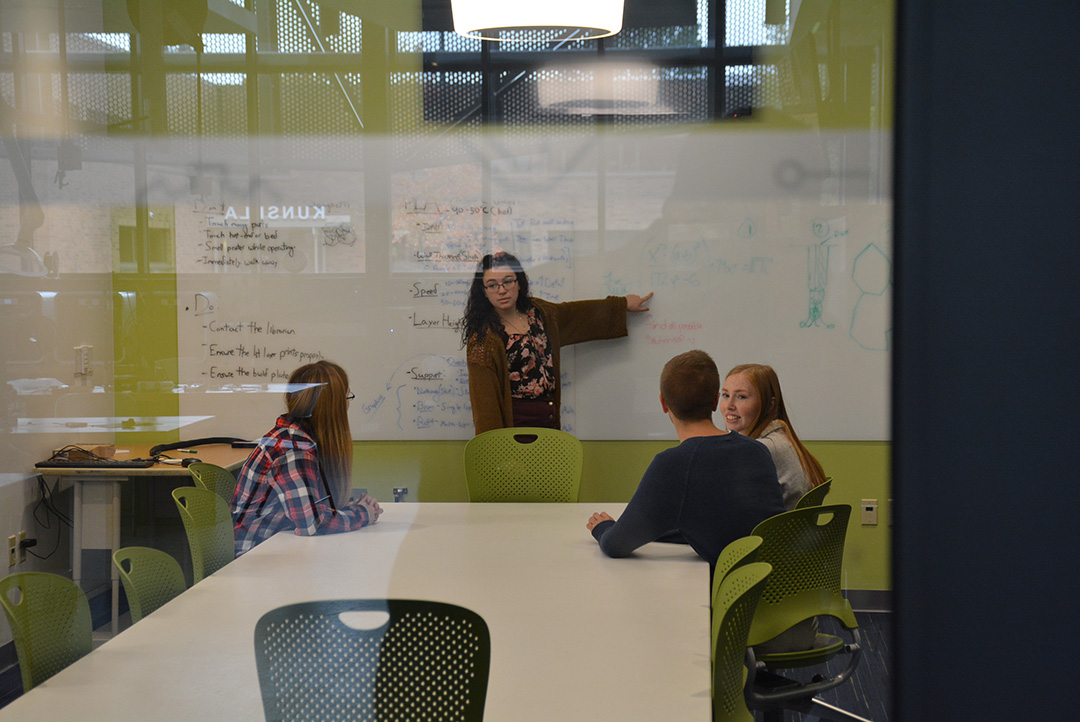 students studying in a group and writing on a whiteboard