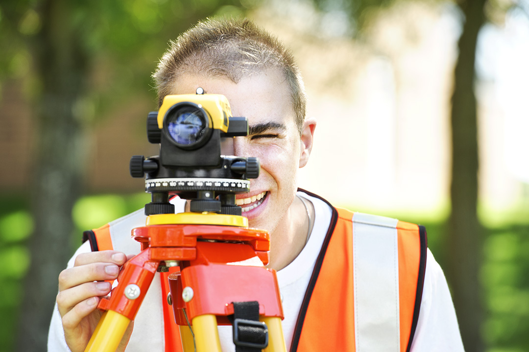 engineering student looking into a surveyor