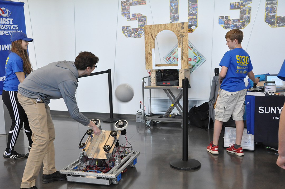students demonstrating a robot throwing a ball